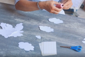 Aus Papier geschnittene Wolken werden mit einem Bindfaden verbunden