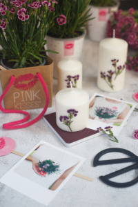 Eine Oberfläche mit Pink Kisses und DIY Kerzen mit gepressten Pink-Kisses-Blüten