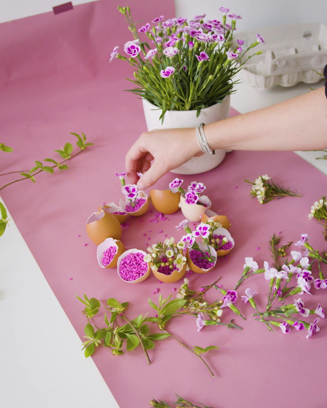 Der Kranz aus Eiern wird mit Deko-Kies, Blumen, Zweigen und Pink Kisses befüllt